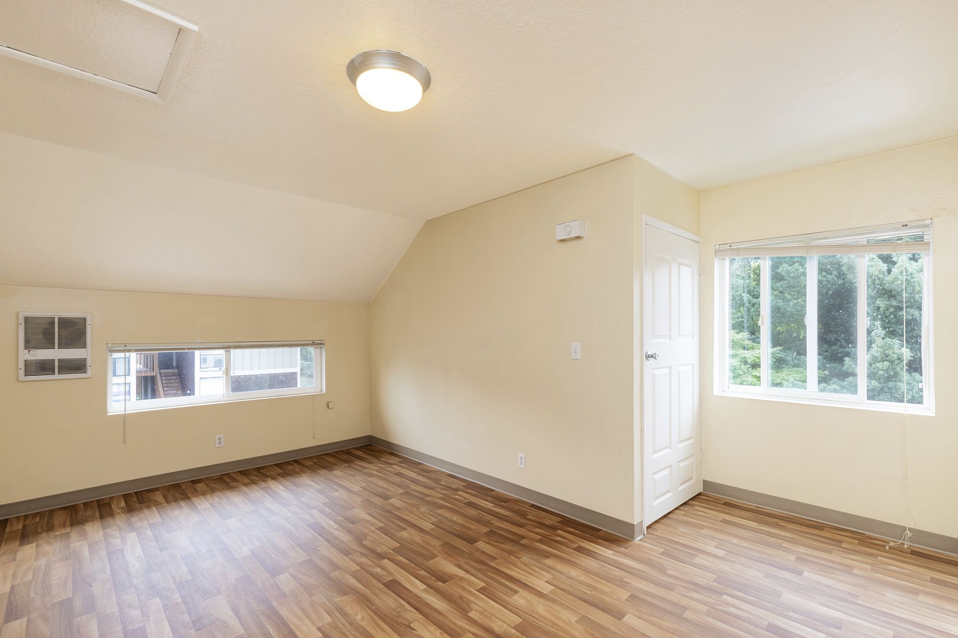An empty room with hardwood floors and two windows.
