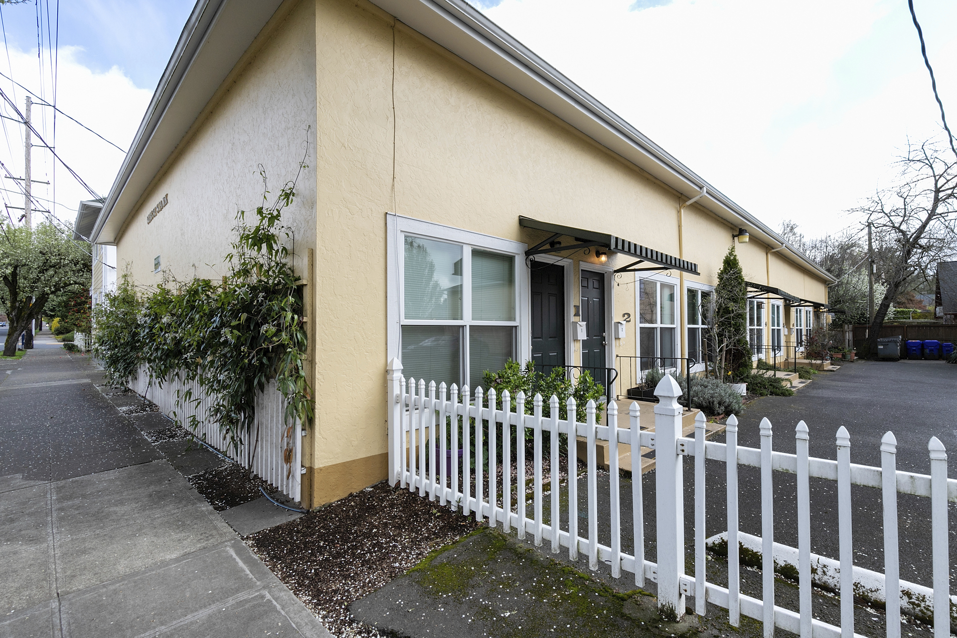 A yellow house with a white picket fence around it