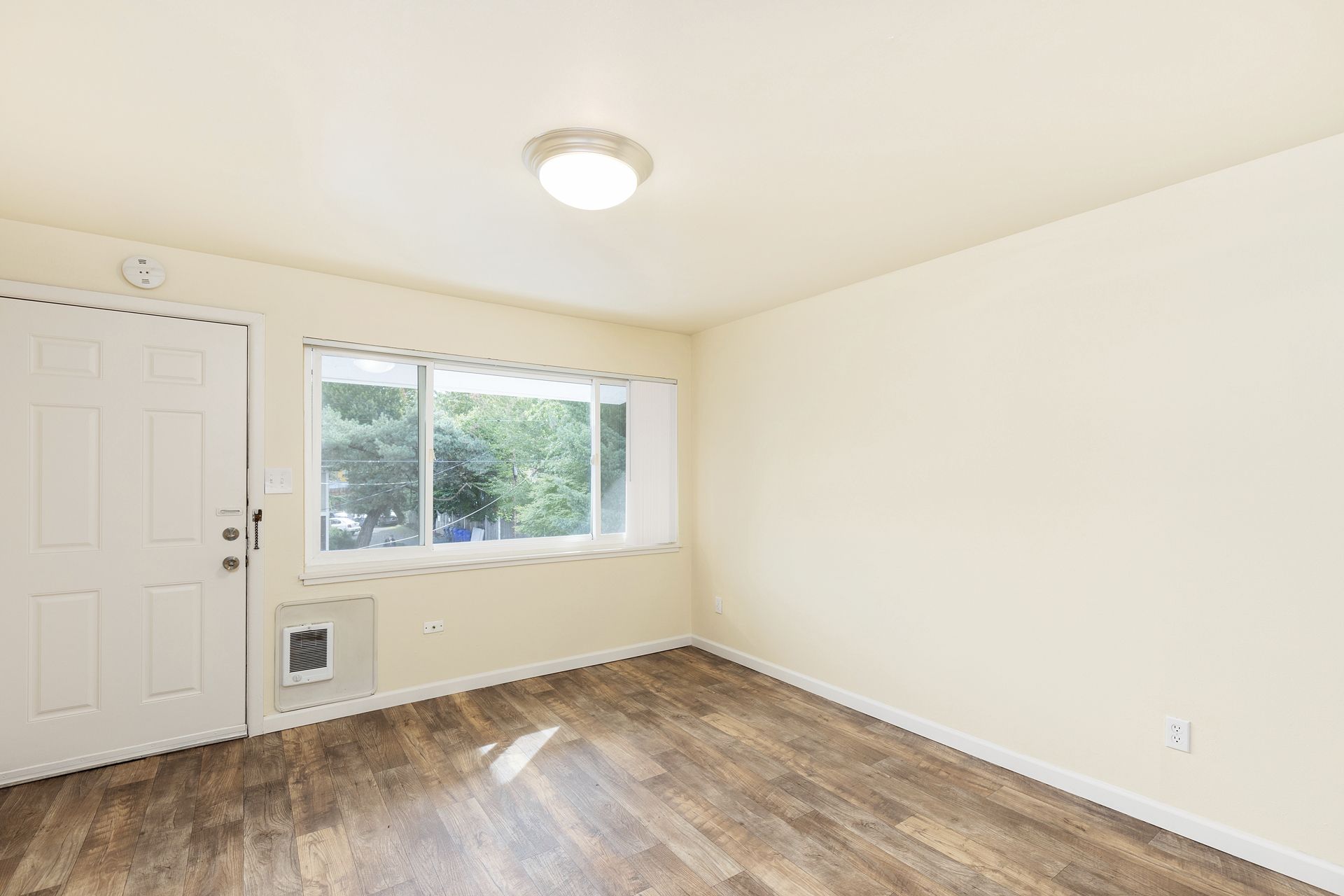 An empty living room with hardwood floors and a window.