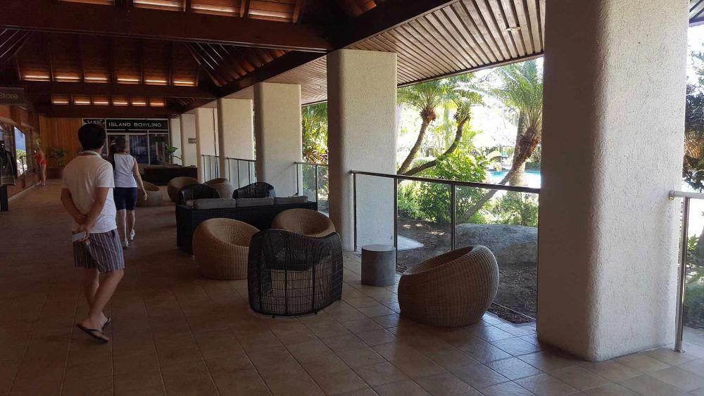 A Man Is Walking Down a Hallway with Chairs and Tables — North Queensland Glass & Glazing In Cannonvale, QLD