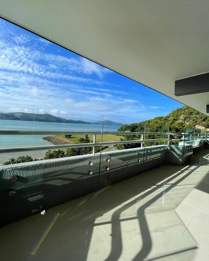 A Balcony with A View of The Ocean and Mountains — North Queensland Glass & Glazing In Cannonvale, QLD