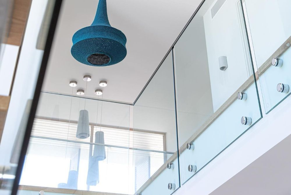 A Blue Pendant Light Is Hanging from The Ceiling Above a Glass Railing — North Queensland Glass & Glazing In Cannonvale, QLD