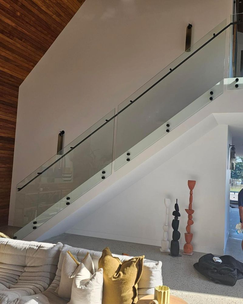 A Living Room with A Couch and Stairs with A Glass Railing — North Queensland Glass & Glazing In Airlie Beach, QLD