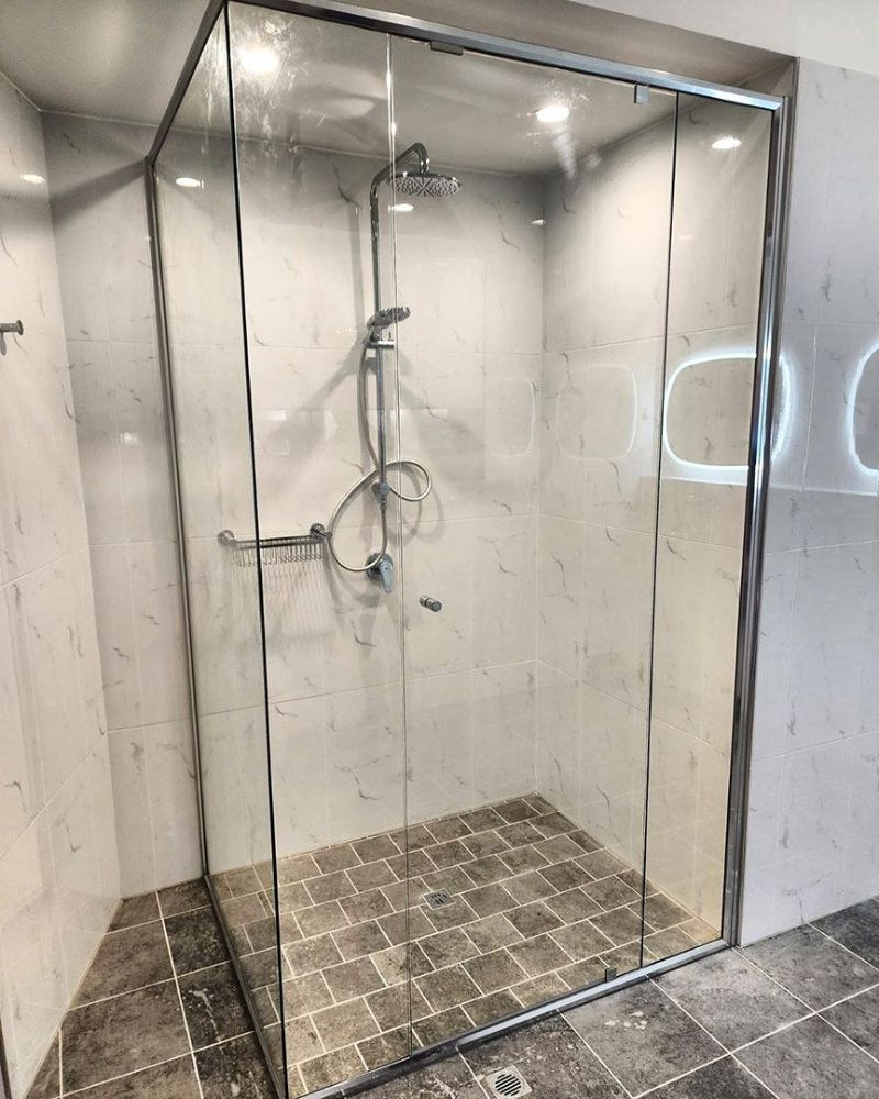 A Shower Stall with Sliding Glass Doors and A Shower Head — North Queensland Glass & Glazing In Cannonvale, QLD