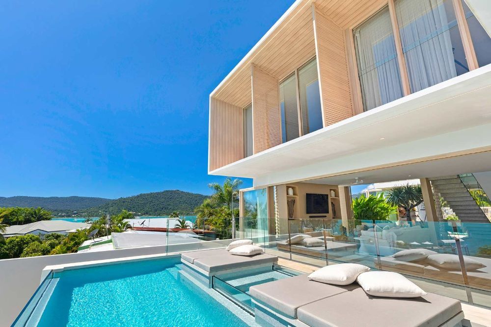 A Large House with A Swimming Pool in Front of It — North Queensland Glass & Glazing In Cannonvale, QLD