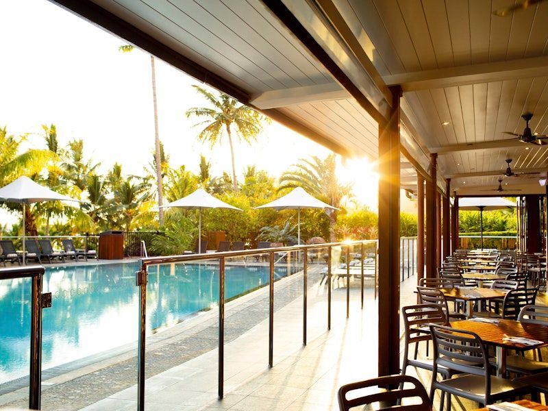 A Restaurant with Tables and Chairs Next to A Swimming Pool β North Queensland Glass & Glazing In Cannonvale, QLD