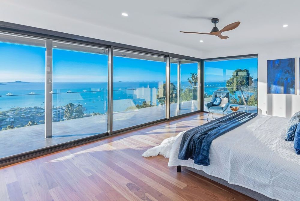 A Bedroom with A Large Bed and Lots of Windows — North Queensland Glass & Glazing In Cannonvale, QLD