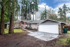 A house with a garage and a driveway surrounded by trees.