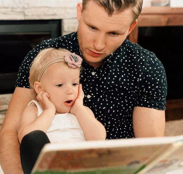 A man is reading a book to a little girl.
