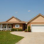 A large brick house with a white garage door and a porch.