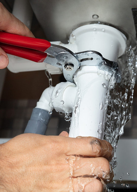 A person is fixing a sink in Westminster, CO pipe with a wrench.