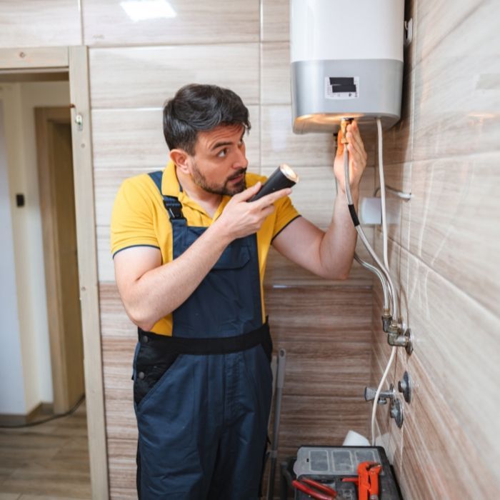 A man is fixing a pipe with a wrench