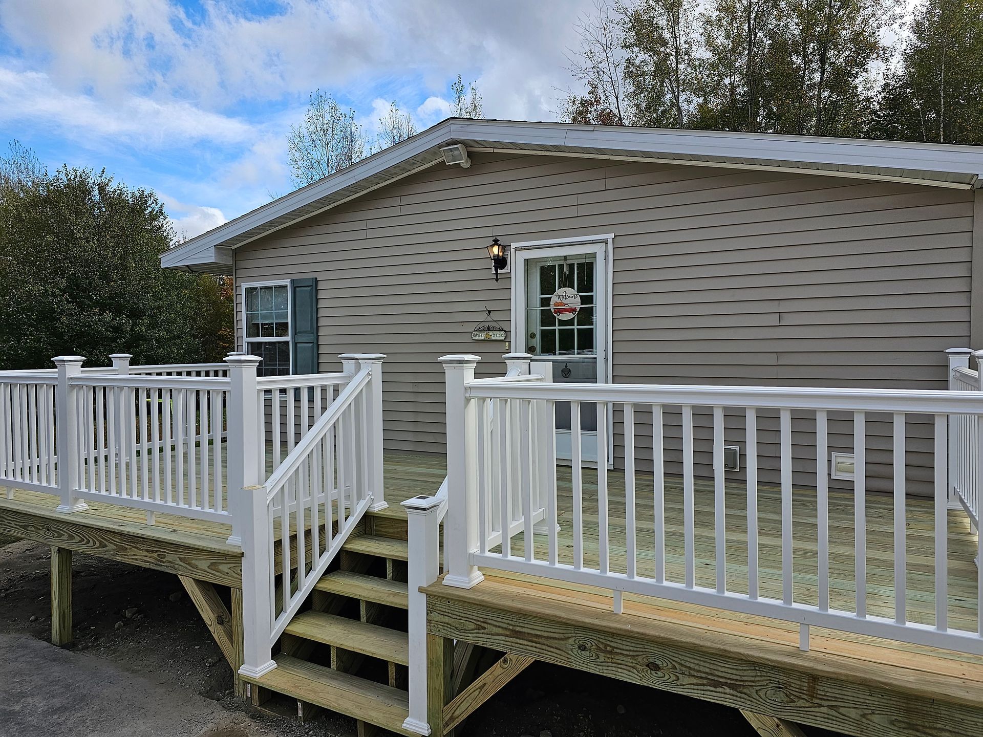 A mobile home with a large deck and stairs leading to it.