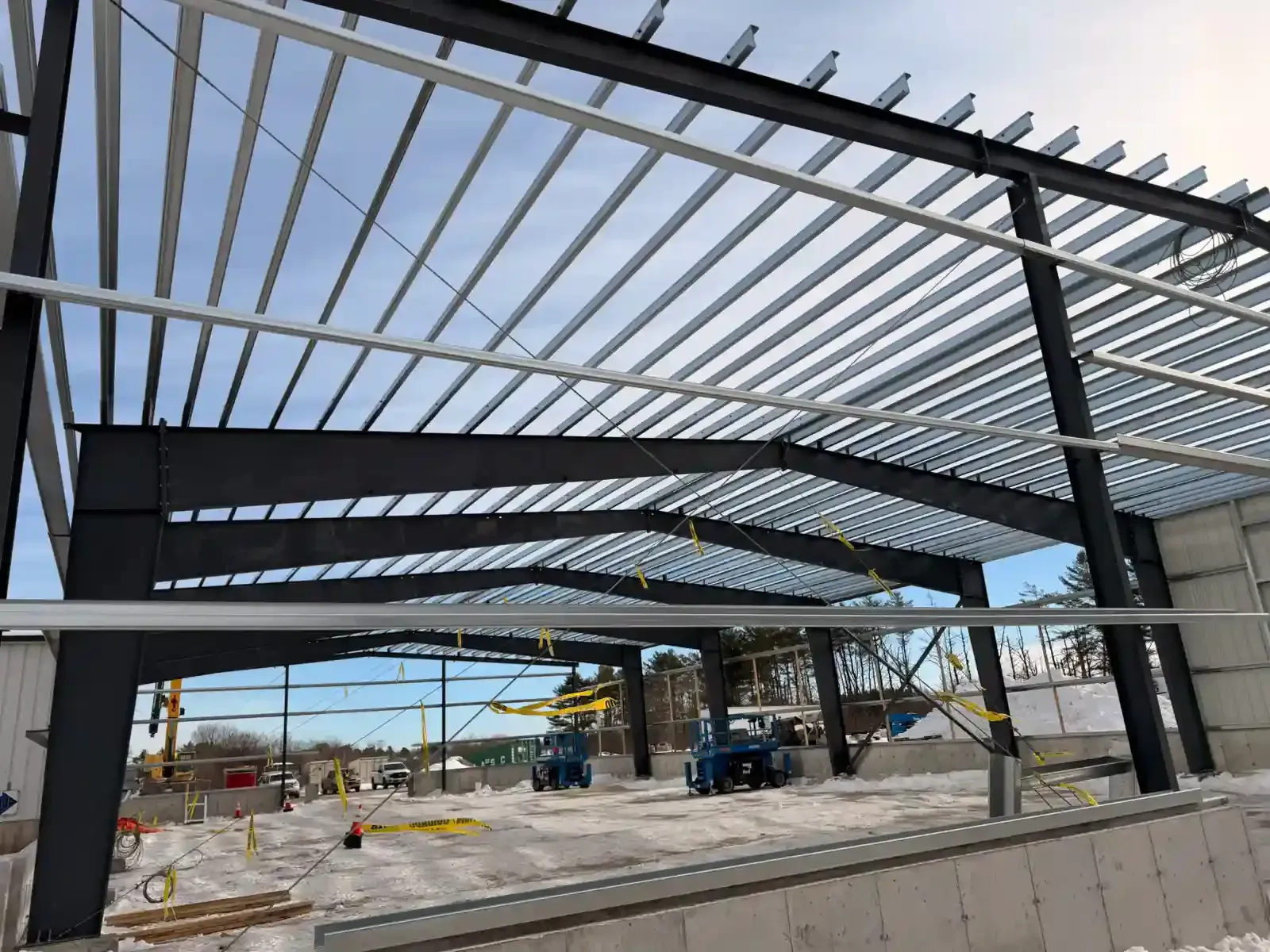 Steel frame of a building under construction with concrete floor and blue sky overhead