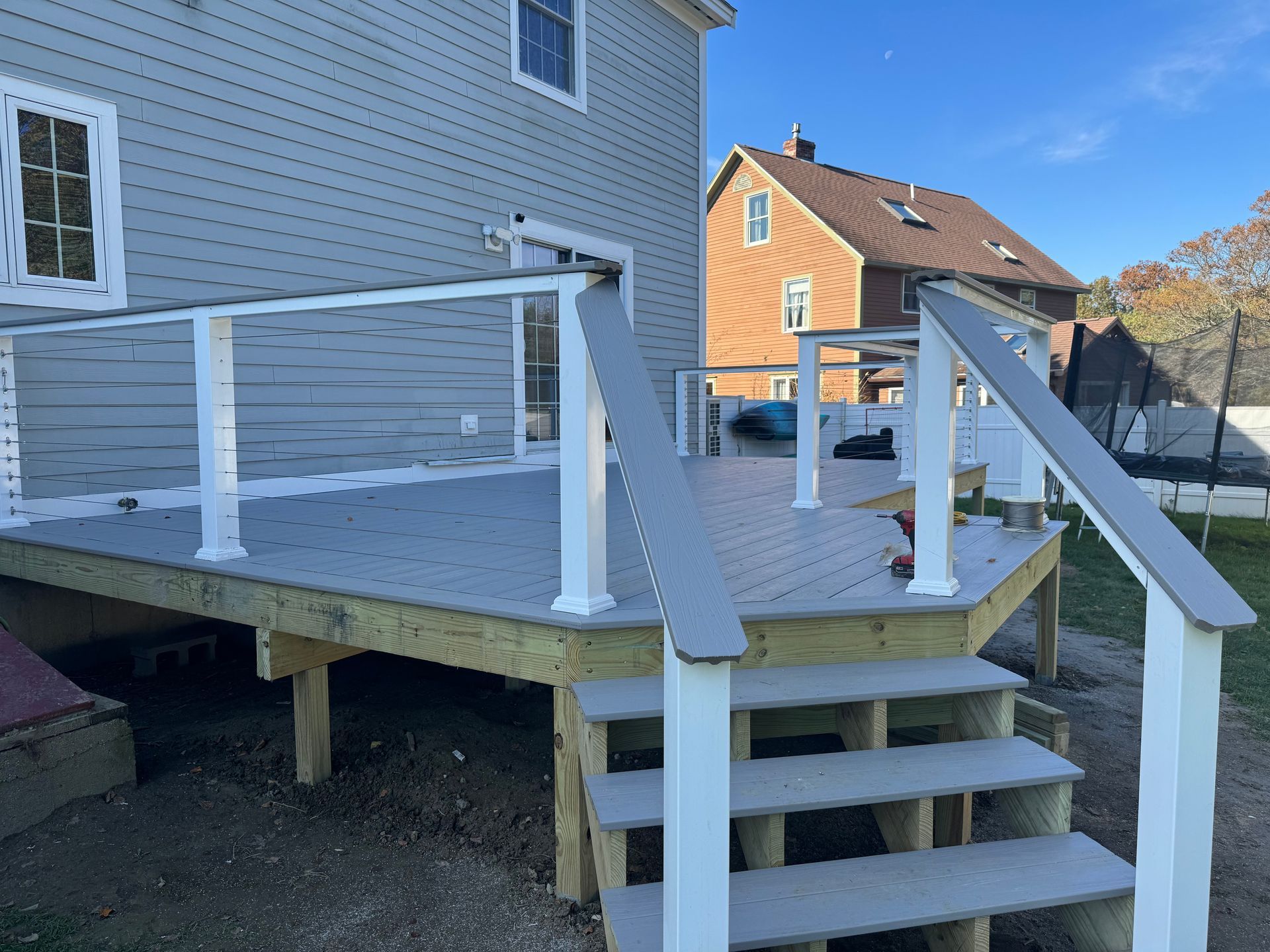A wooden deck with stairs and a white railing in front of a house.
