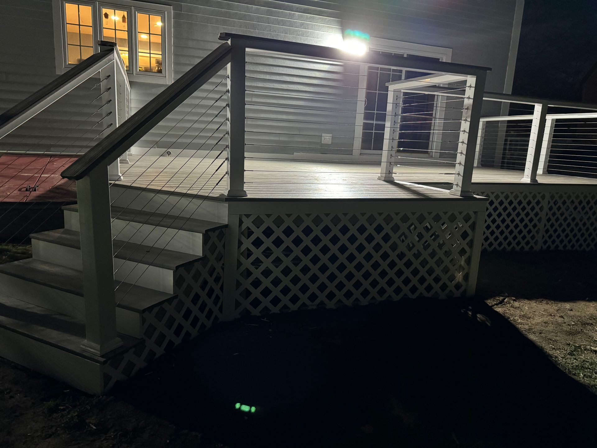 A deck with stairs and a railing is lit up at night