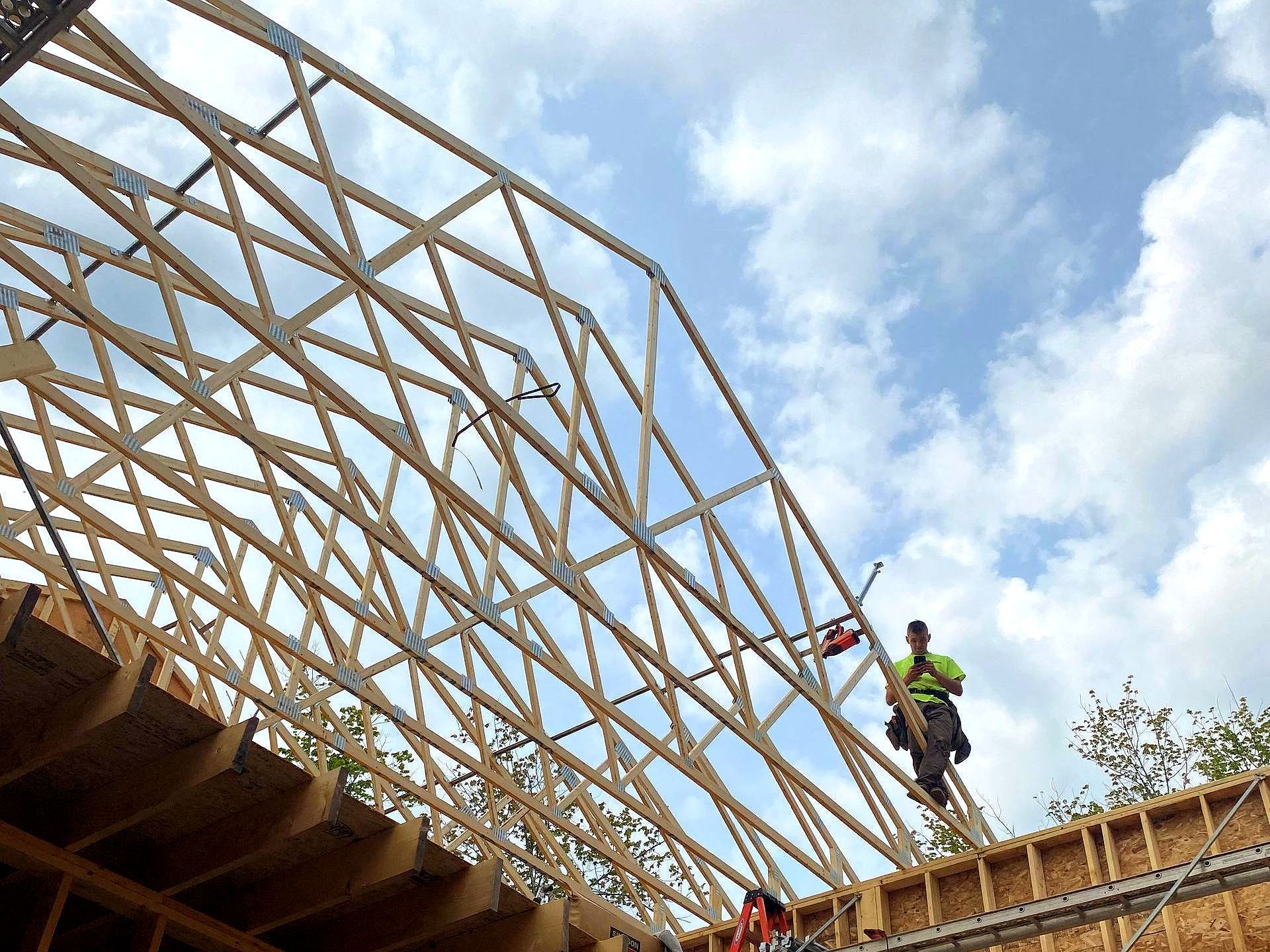 a framing job site with a carpenter standing on trusses