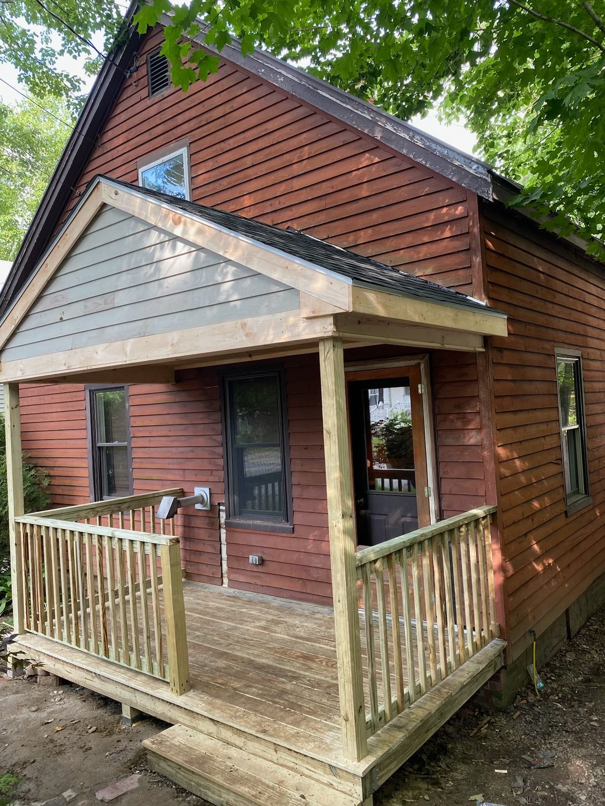 A small house with a porch and a wooden deck.