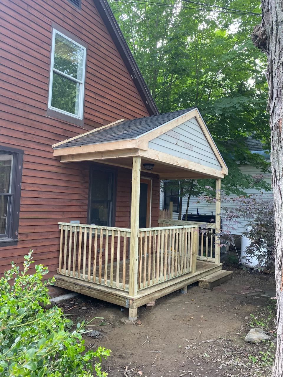 a newly constructed porch on a house with red siding
