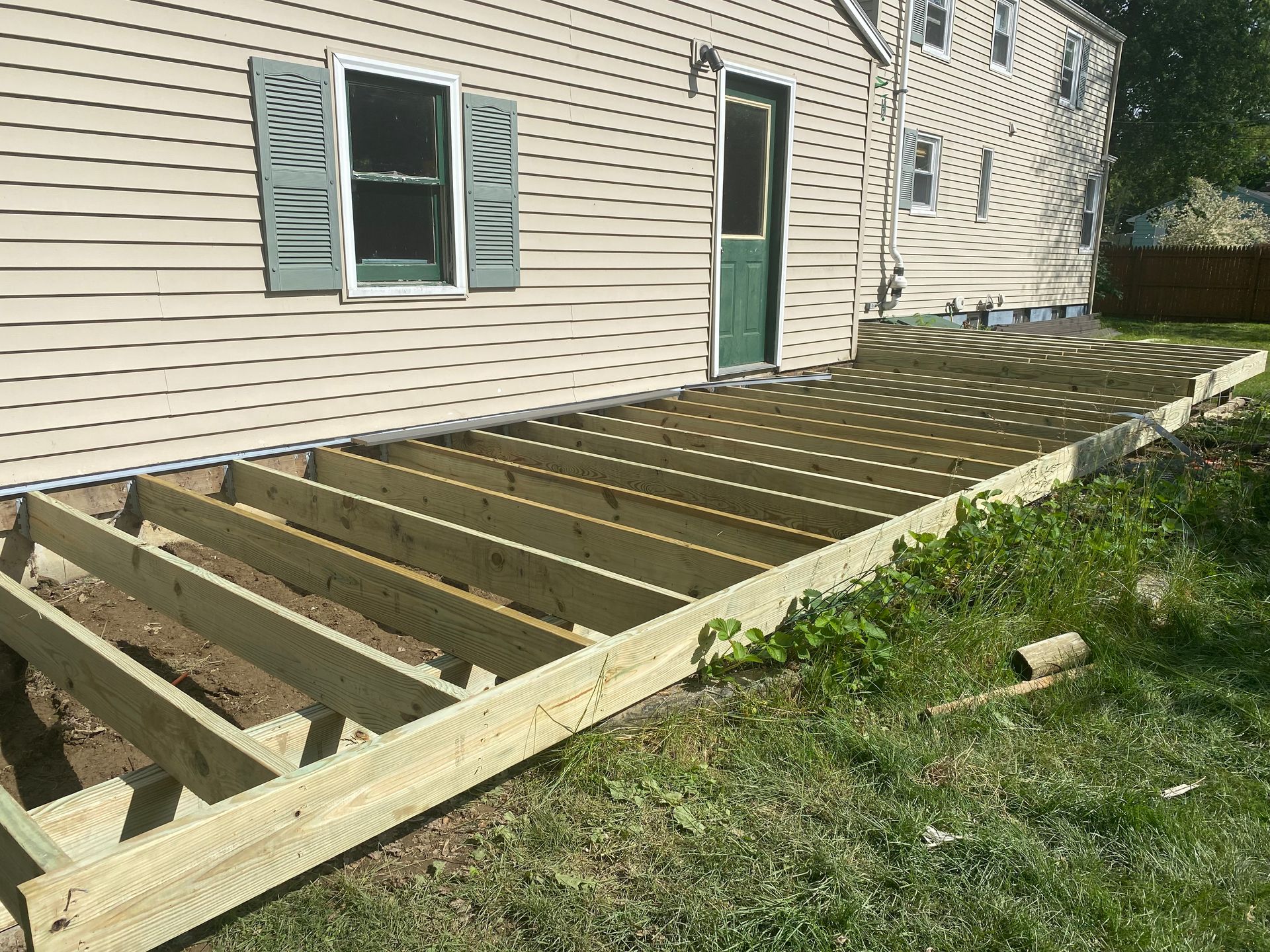 A wooden deck is being built in front of a house.