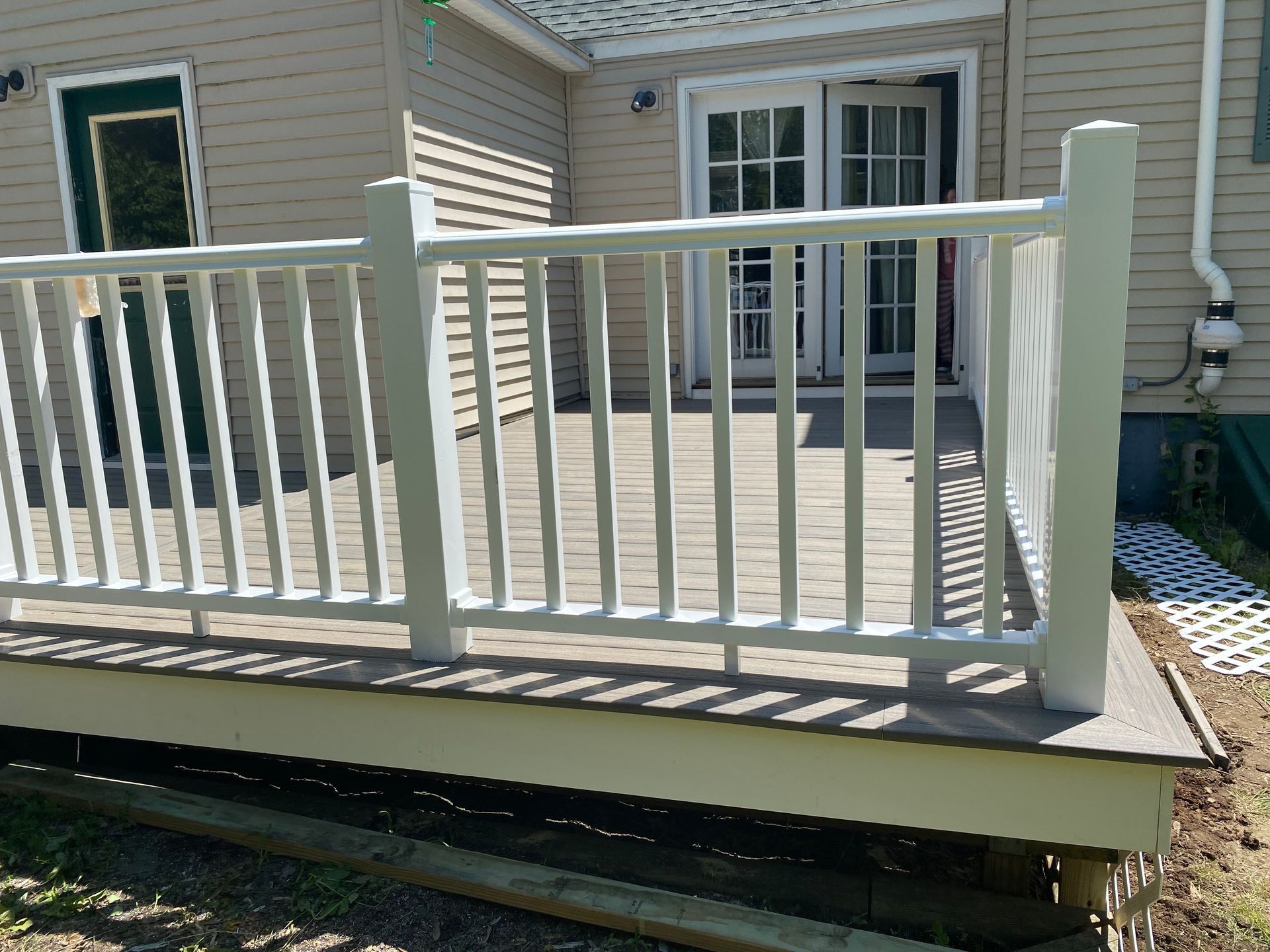A white deck with a white railing is in front of a house.
