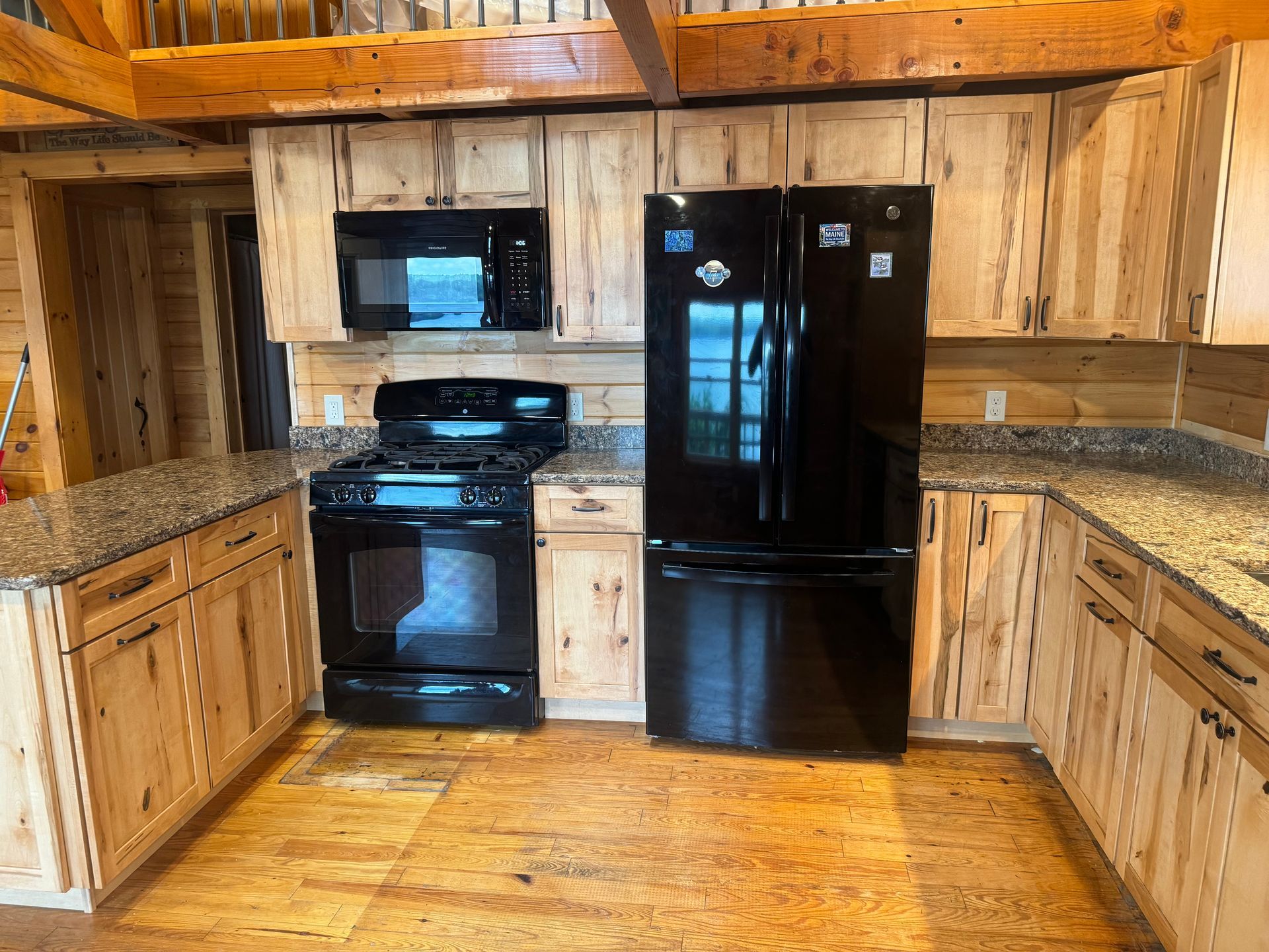 A kitchen with wooden cabinets and a black refrigerator