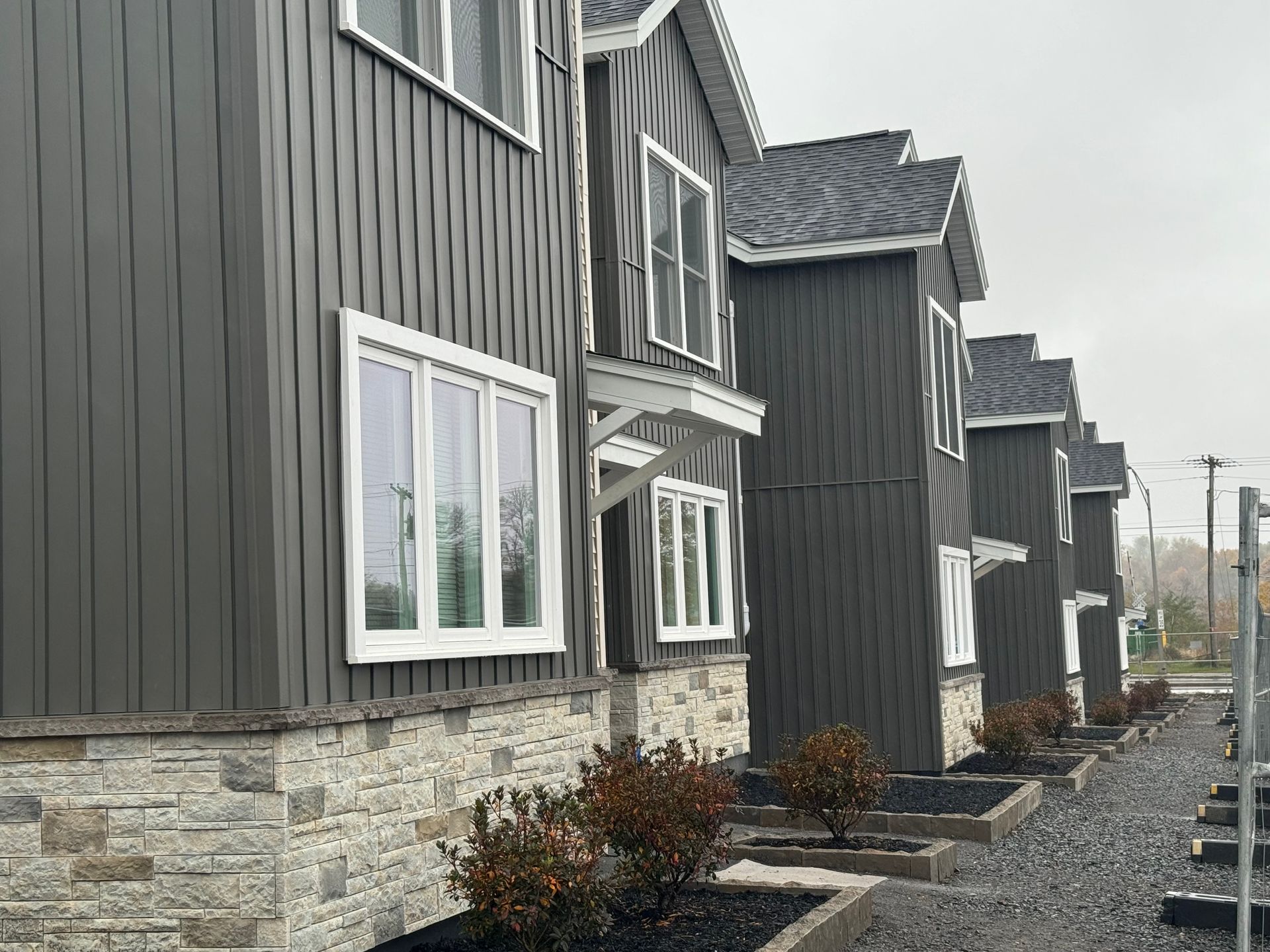 a row of new construction multi family houses with grey siding and white windows