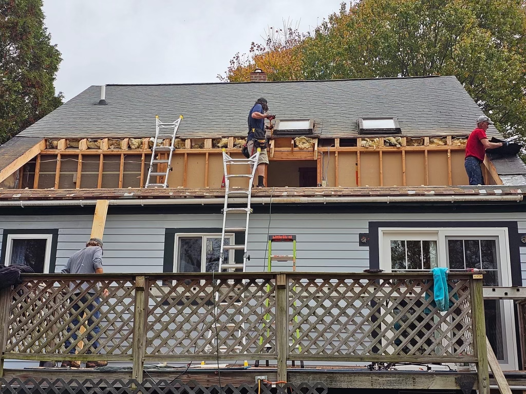 two men are working on the roof of a house building a new roof
