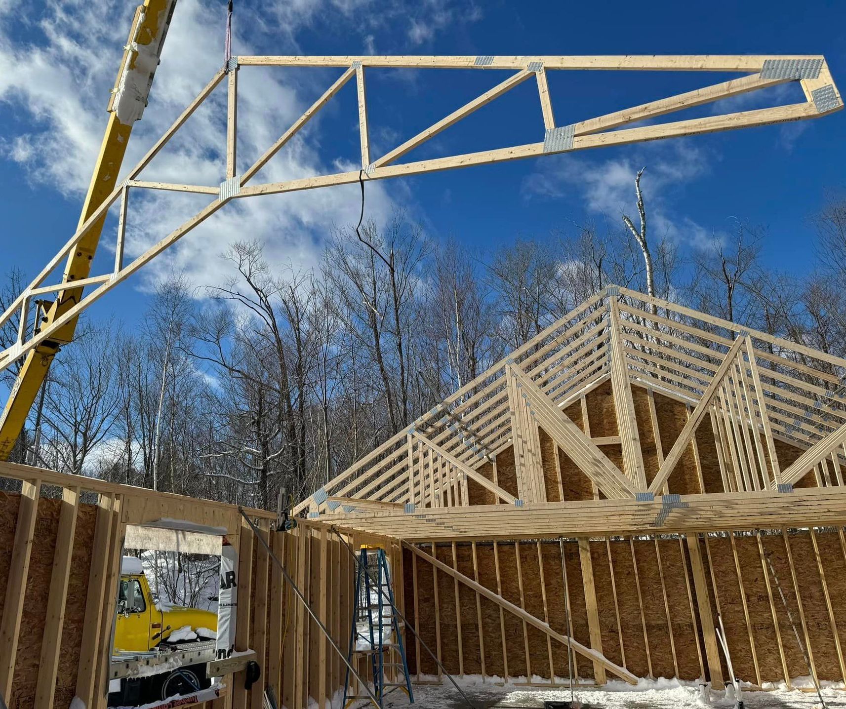 a crane hoisting a truss on a framing job site