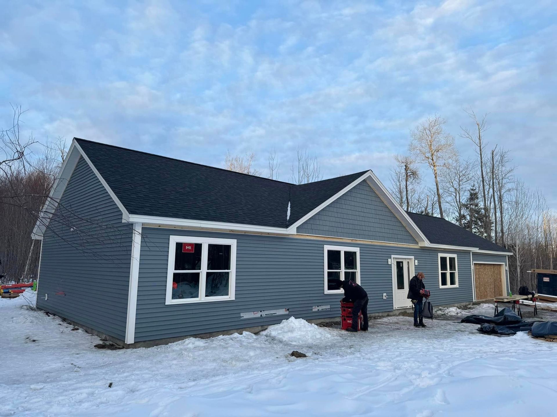 contractors in front of a ranch home with blue siding in the winter