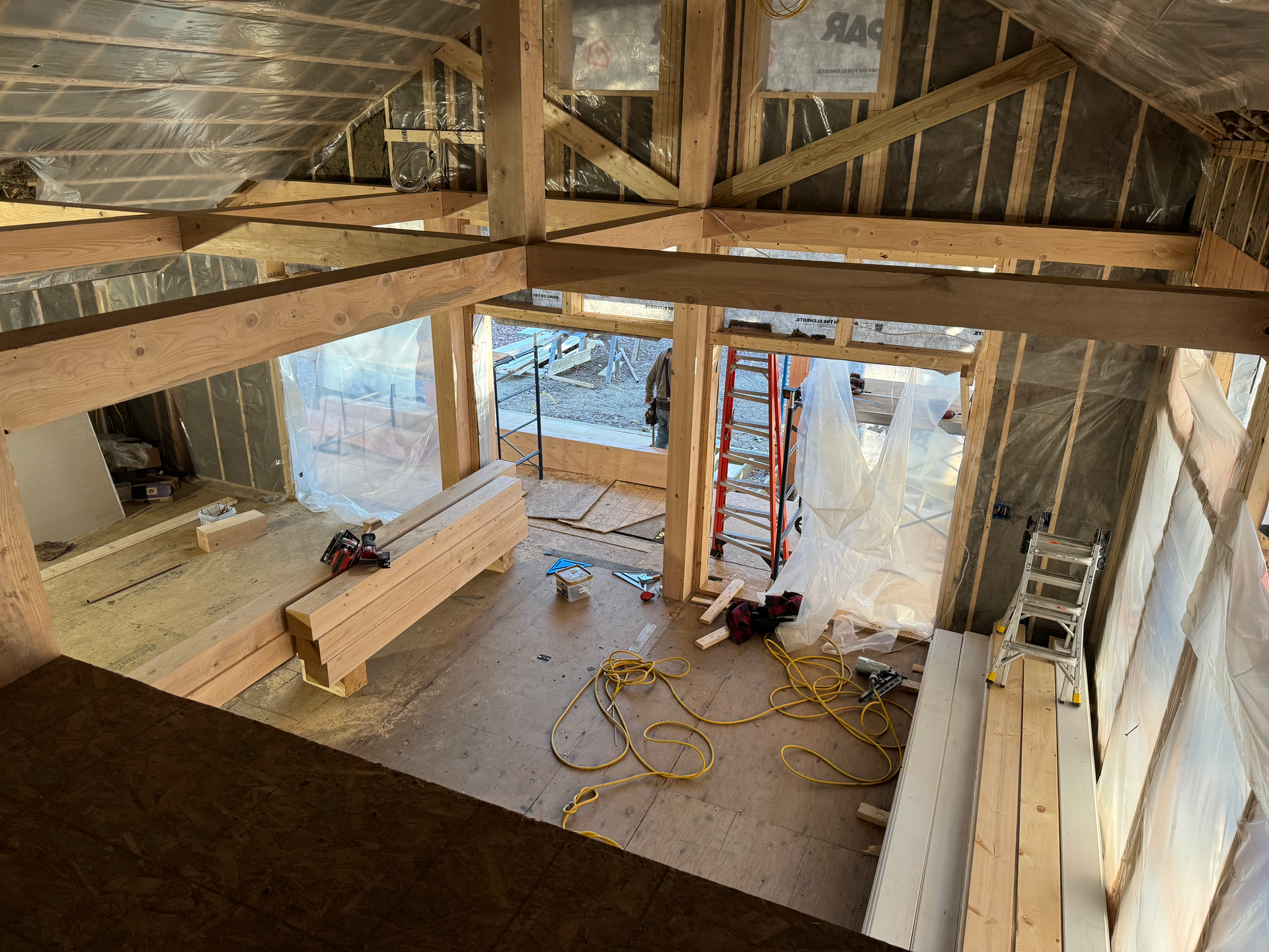 A timber frame under construction with a ladder in the middle