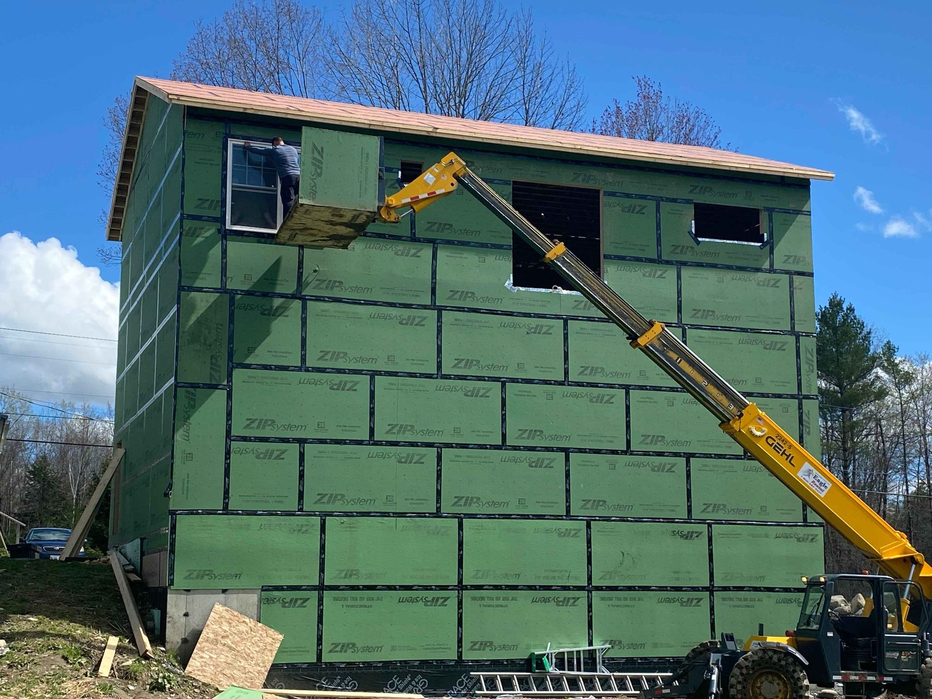 A yellow crane is lifting a window from a building under construction.