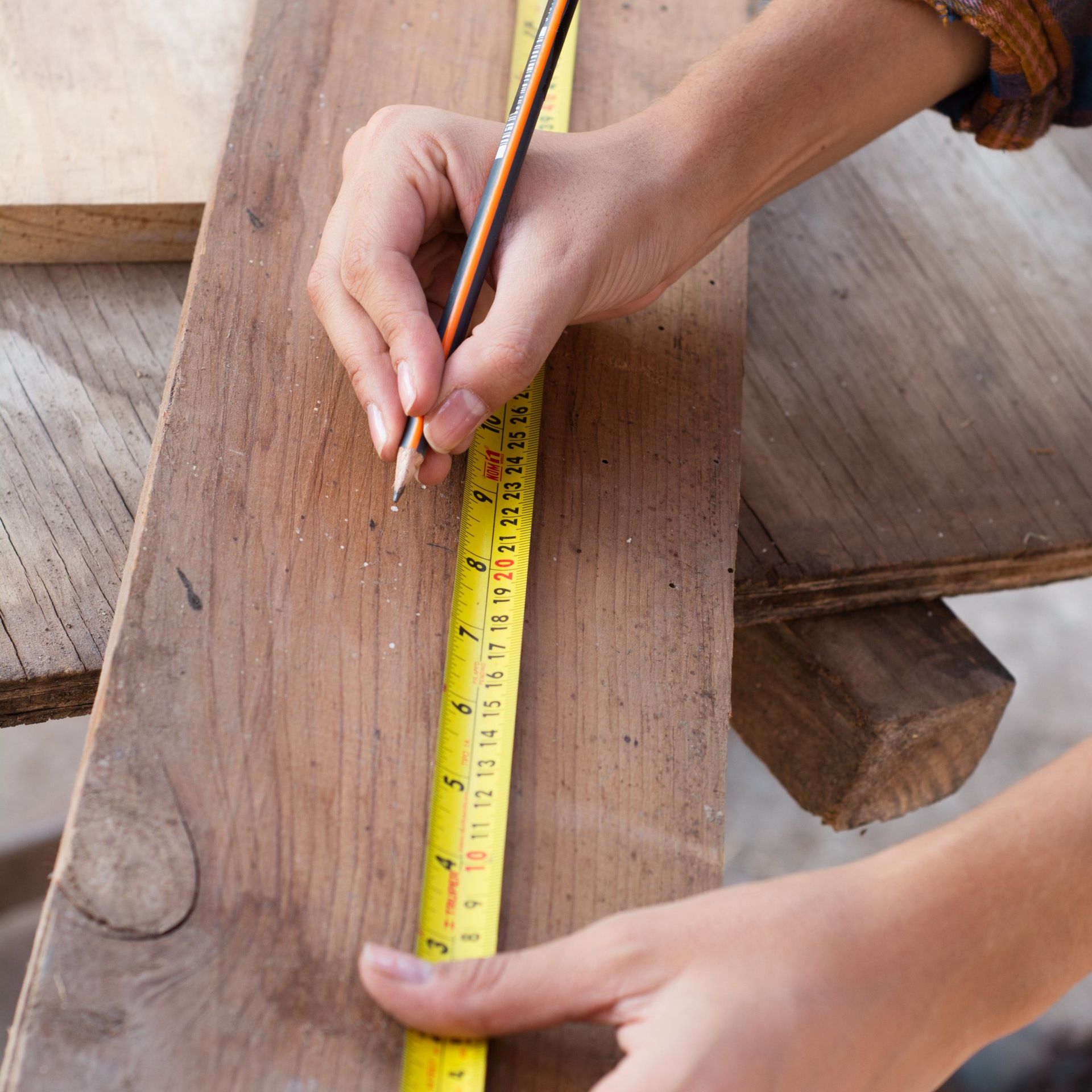 a contractor is measuring a piece of wood with a tape measure