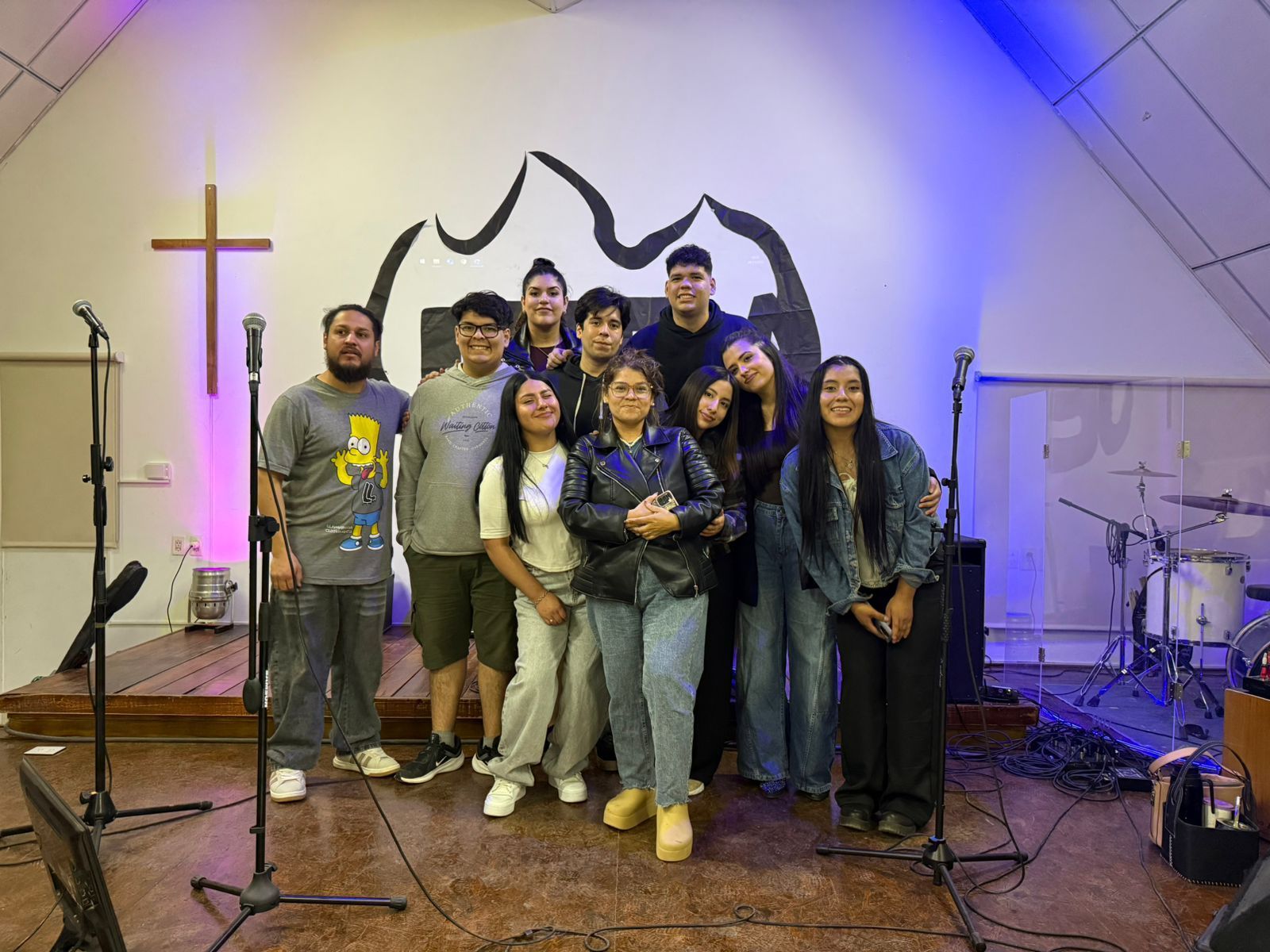 Mujer hablando por un micrófono en un podio, gesticulando. Fondo de pared blanca.