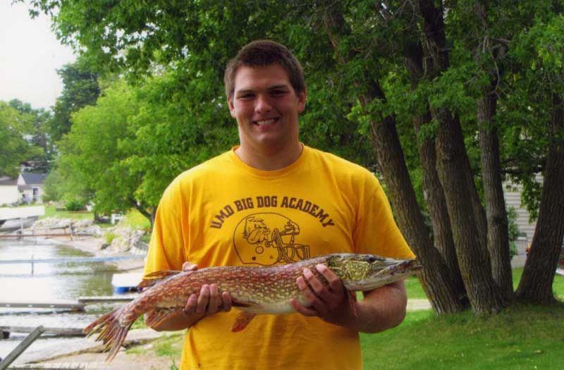 A man in a yellow shirt holding a large fish
