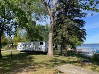 A man is carrying two children on his shoulders in a field.