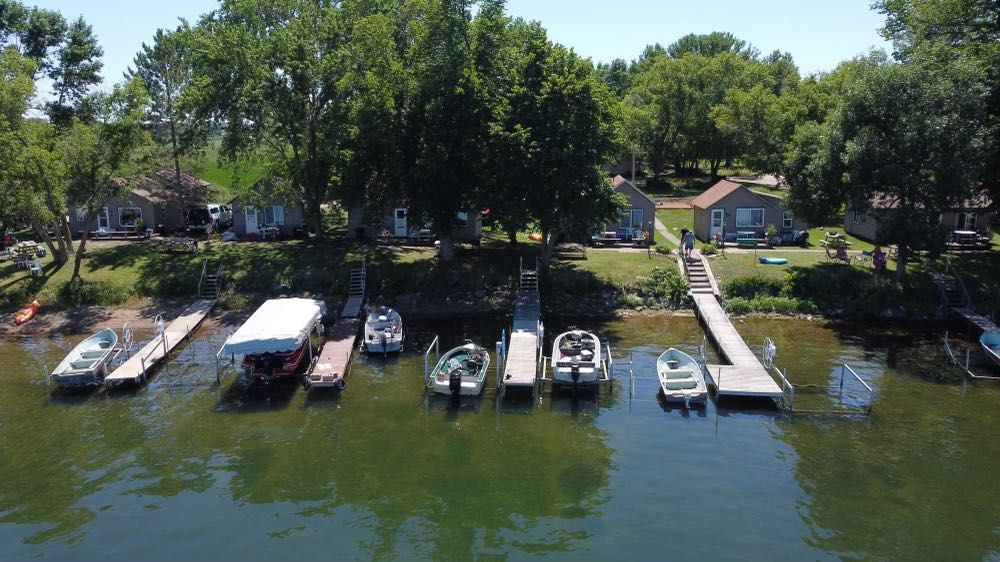 A group of boats are docked at a dock on a lake.