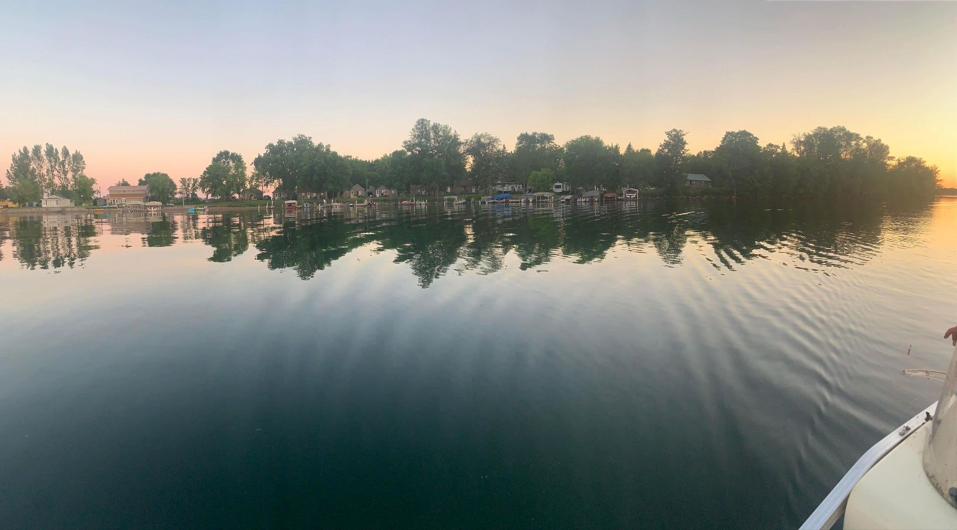A dog is standing on a boat in the water near a small island.