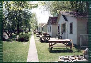 A row of white houses with picnic tables in front of them