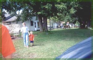 A woman and a child are walking in a park holding hands.