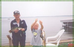 A man and a boy are standing next to each other holding fish.