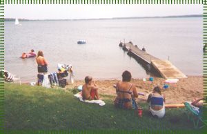 A group of people are sitting on the grass near a lake.