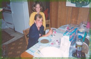 Two children are sitting at a table with a bowl of soup.