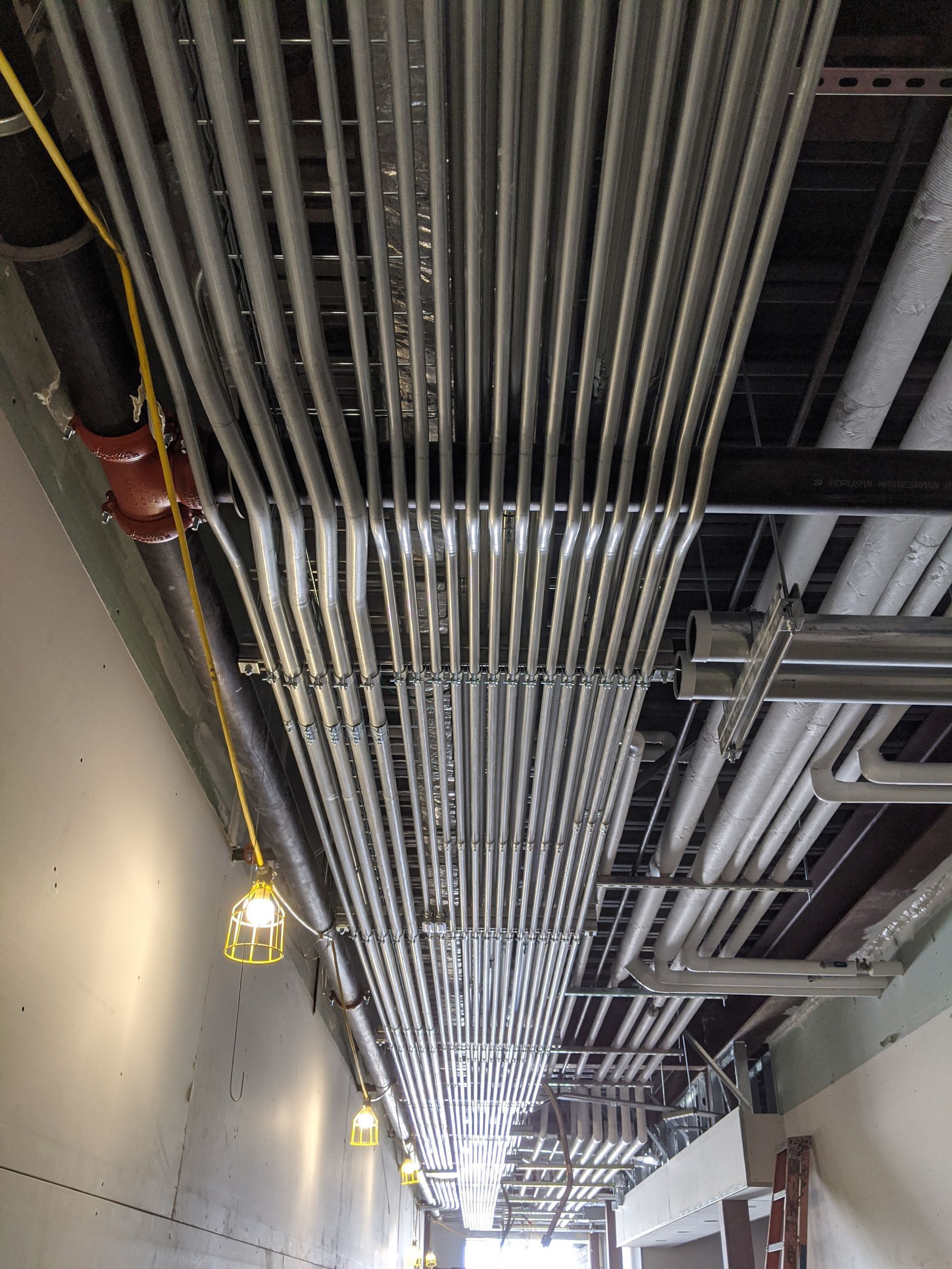 Freedom Electric Construction - A bunch of pipes are hanging from the ceiling of a building.