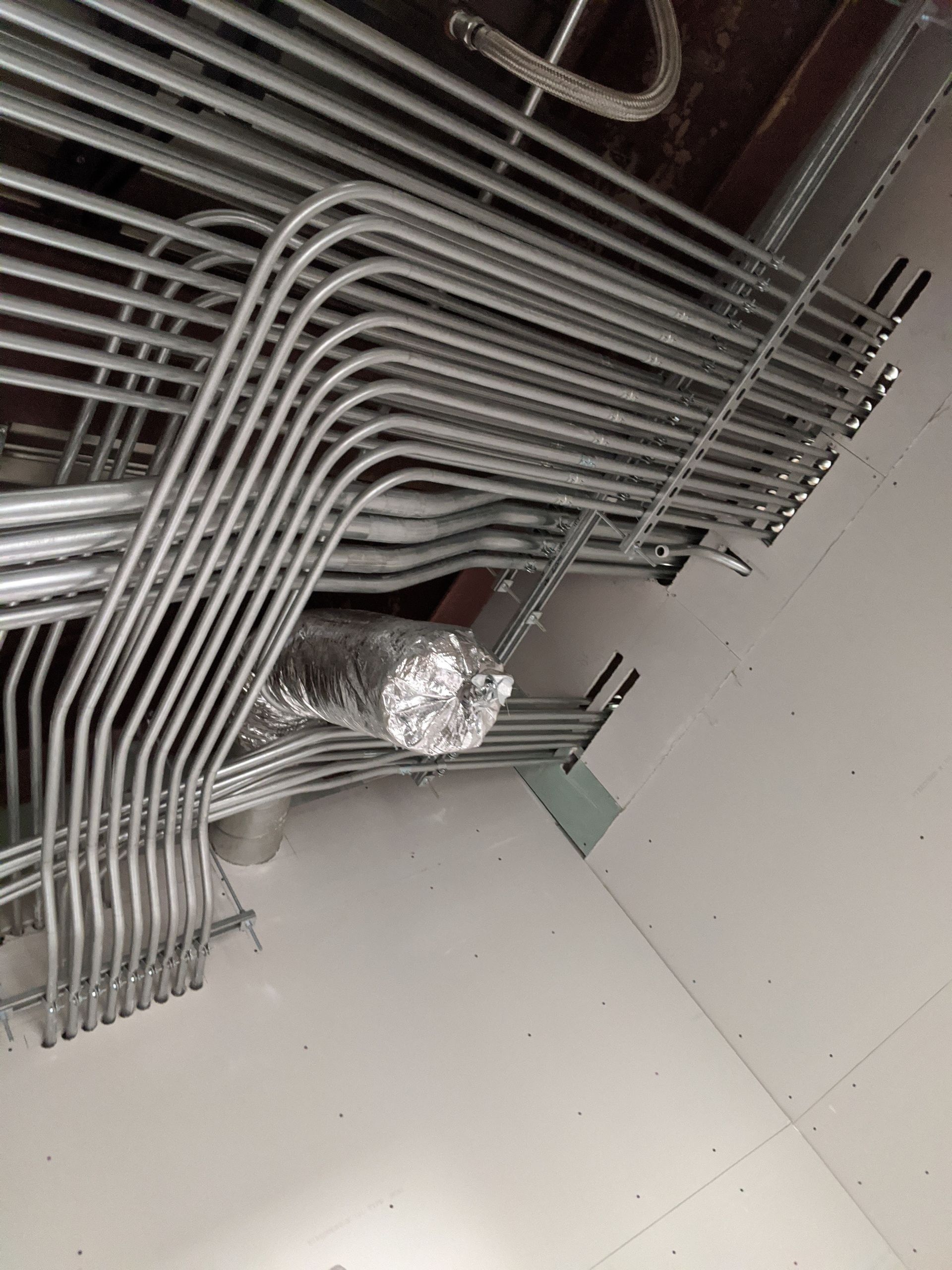 Freedom Electric Construction - A bunch of metal pipes are hanging from the ceiling of a building.