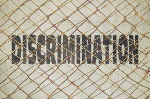 chainlink fence in front of the word discrimination