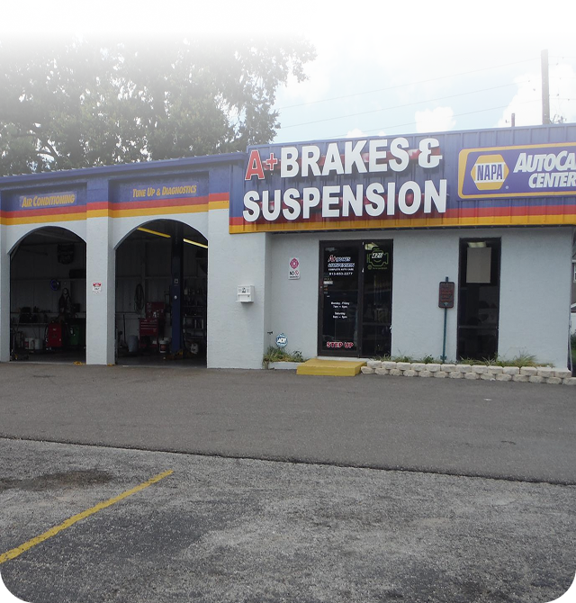 A+ Brakes & Suspension auto repair shop with garage bays, under a blue, yellow and red banner. | A+ Brakes & Suspension