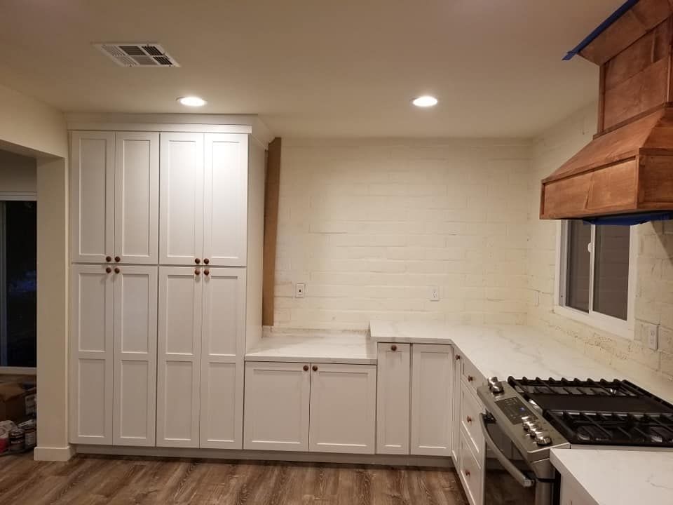 JJR Construction -  White kitchen cabinets and countertops, copper range hood, gas stovetop.