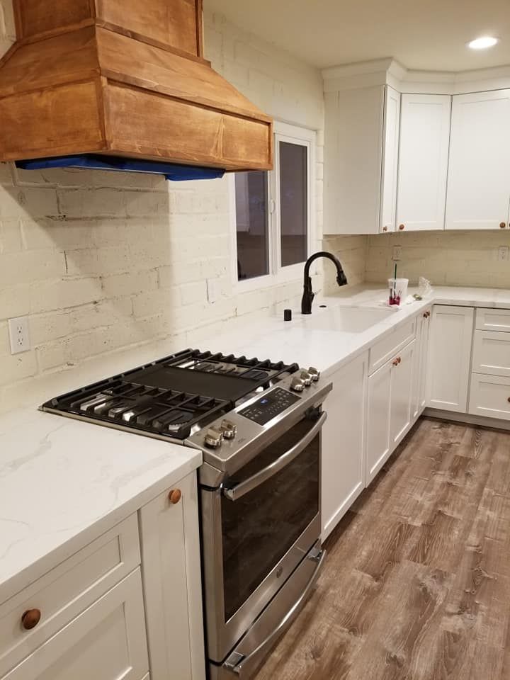 JJR Construction -  White kitchen with copper range hood, stainless steel appliances, and white countertops.