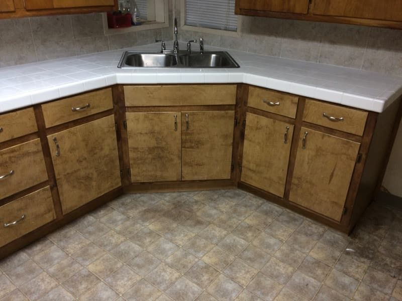 JJR Construction - Kitchen corner with light countertop, wooden cabinets, and stainless steel sink.